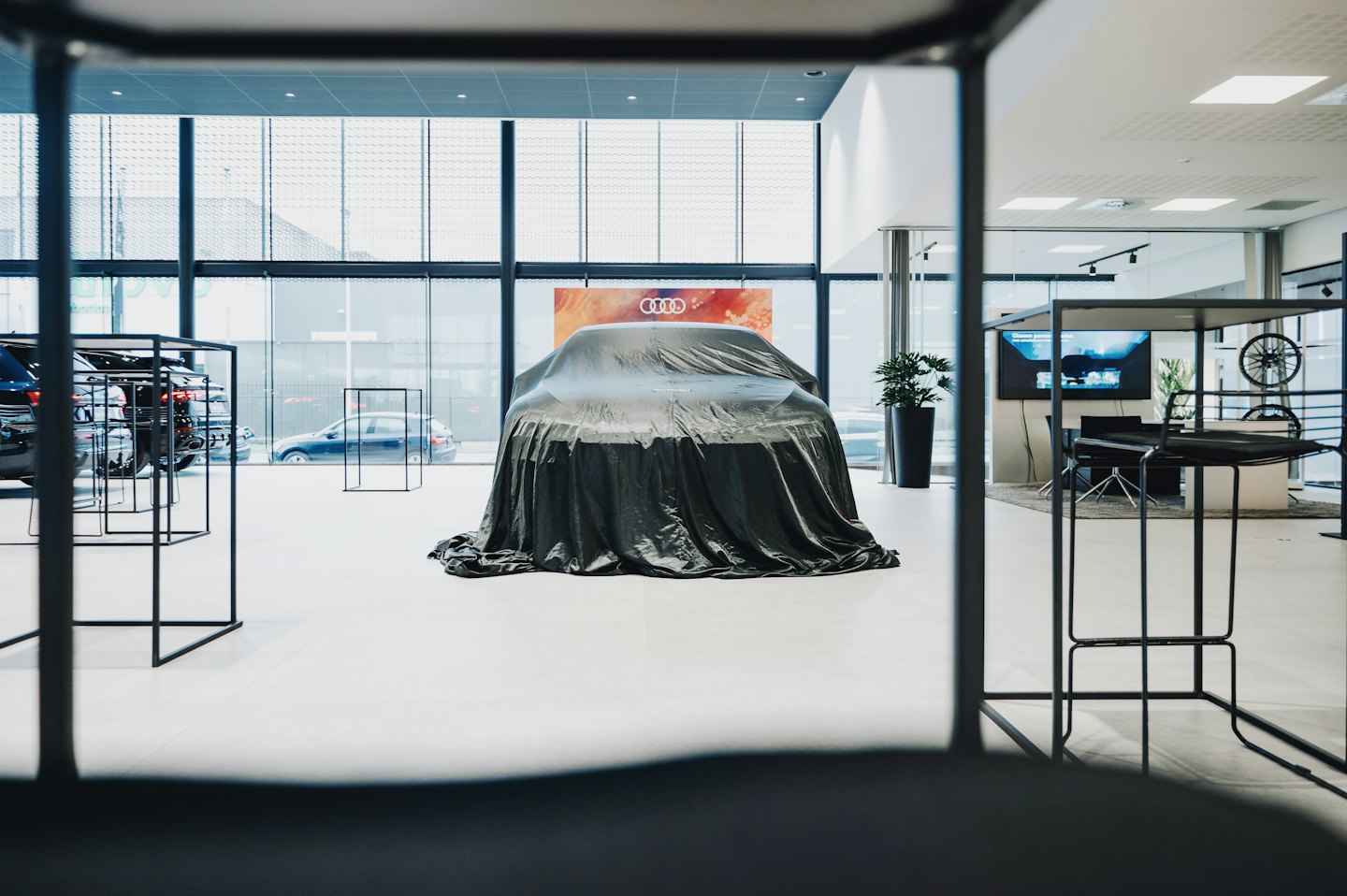 Un'auto coperta si trova al centro di uno showroom moderno.